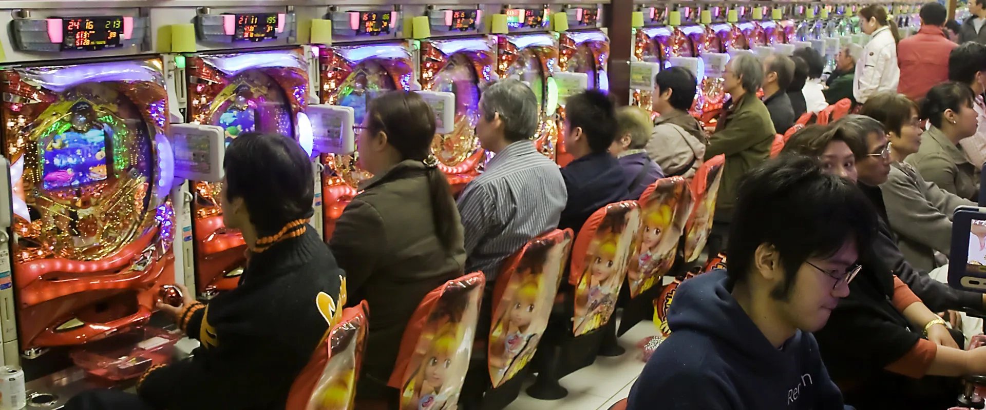 Imagem de várias pessoas jogando pachinko em maquinas eletromecânicas